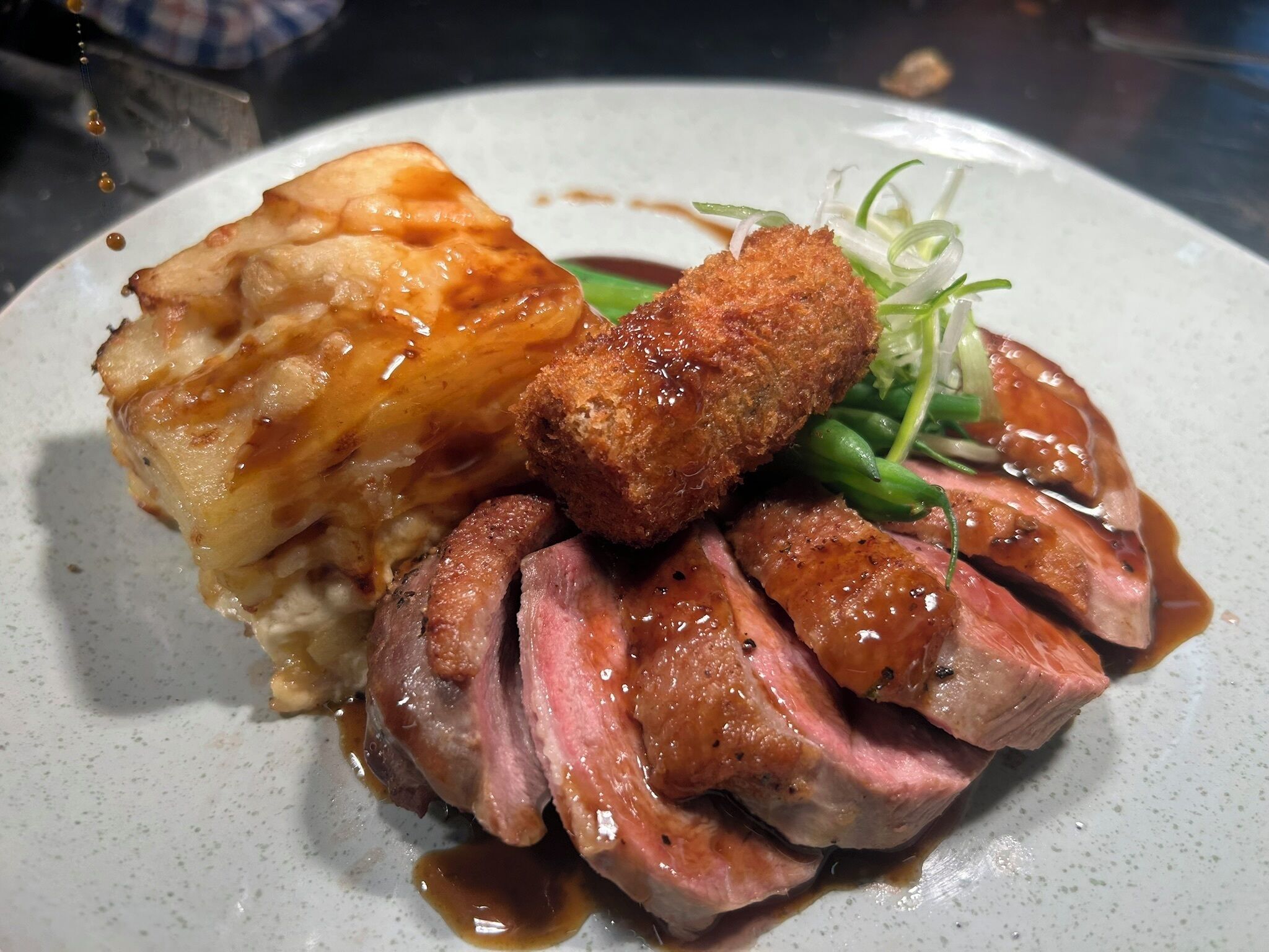 A plate of food with sliced meat, a breaded item, and a side dish.