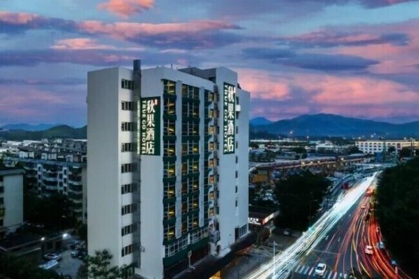 A modern hotel with multiple floors and balconies, surrounded by a busy urban area with visible roads and distant mountains. - Qiuguo Hotel Shenzhen  Huanggang Port (Shenzhen)