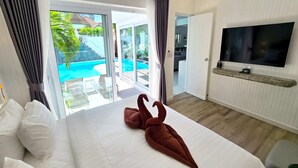 A hotel room with a bed, a TV, and a view of a pool. - LUMALAND Luxury Pool Villa Pattaya Walking Street (Pattaya)