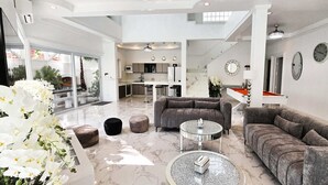 A spacious living area with a modern design, featuring a grey sofa set, a coffee table, and a dining area with a pool table. - LUMALAND Luxury Pool Villa Pattaya Walking Street (Pattaya)
