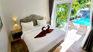 A hotel room with a bed, a nightstand, a lamp, and a view of a swimming pool. - LUMALAND Luxury Pool Villa Pattaya Walking Street (Pattaya)