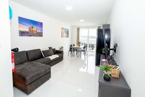 Ein modernes Wohnzimmer mit einer Eckcouch, einem Essbereich und einem Balkon mit Blick.