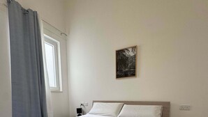 Cama bem arrumada com toalhas dobradas, mesa de cabeceira com controle remoto e um quadro pendurado na parede.