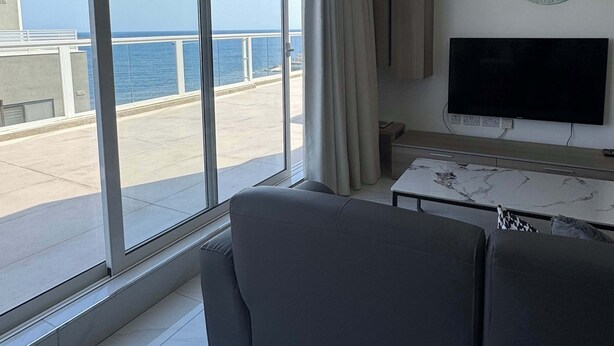 Una sala de estar moderna con un ventanal grande, un televisor de pantalla plana y una mesa de centro de mármol.