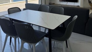 Una sala de estar moderna con una mesa de comedor, sillas, un sofá, un televisor y un reloj en la pared.