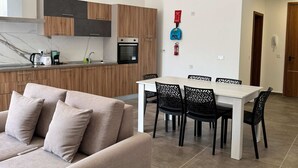 Una cucina moderna con mobili in legno, un tavolo da pranzo con sedie e un divano color beige.