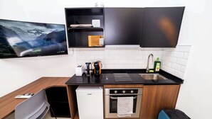 Uma cozinha compacta com lava-louças embutida, forno e uma pia pequena.