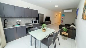 Una cocina moderna con armarios grises, una mesa de comedor con sillas y una mesita auxiliar con una planta.