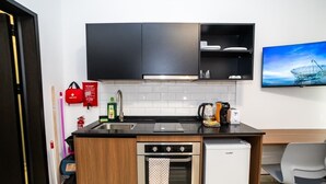 Ett kompakt kök med diskmaskin, ugn och kaffebryggare.