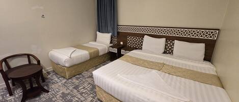 A hotel room with two single beds, a wooden chair, and a patterned carpet.