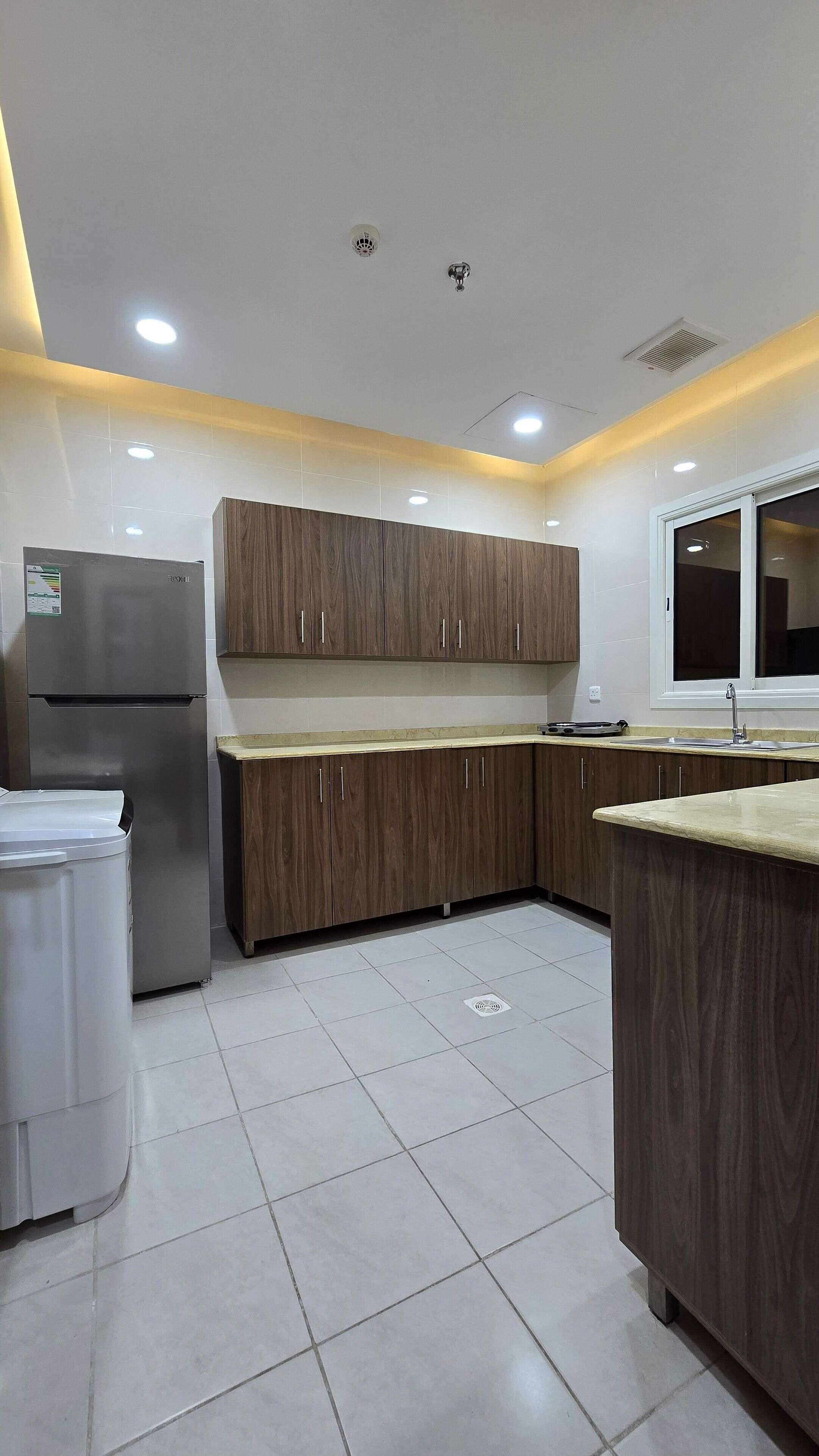 A modern kitchen with wooden cabinets, a stainless steel refrigerator, and a sink.