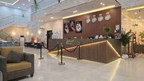 A reception area with a wooden reception desk, multiple clocks, and a staircase in the background. - Knoz Al Anood Hotel Makkah (Makkah)