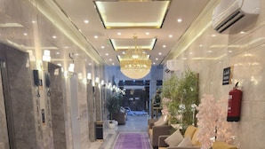 A hotel lobby with a purple carpet, marble walls, a chandelier, and seating areas.