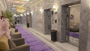 A hotel lobby with a purple carpet, marble walls, and a chandelier.