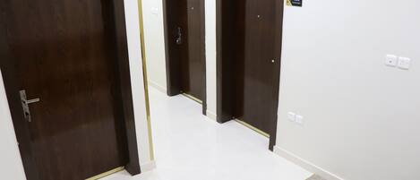 Um corredor com três portas de madeira, cada uma com uma placa indicando o número do quarto.