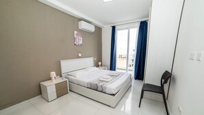 Een moderne slaapkamer met een bed, nachtkastjes, een stoel en uitzicht op buiten.