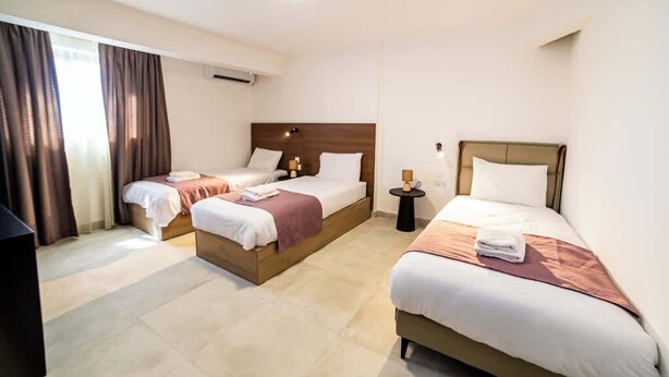 Una camera d'albergo con due letti, un tavolino e una televisione.