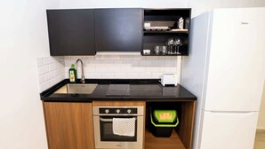 Una cucina compatta con forno a incasso, lavello e frigorifero.