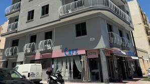 Un edificio a più piani con balconi, un caffè al piano terra e una motocicletta parcheggiata.