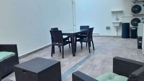 A patio area with a glass table and chairs, surrounded by wicker furniture. - Comfortable 3-Bedroom Seaside Stay (St. Paul's Bay)