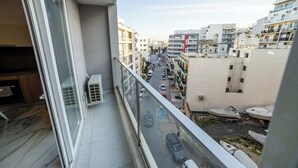Un balcon donnant sur une rue de la ville, des immeubles et des bateaux amarrés.