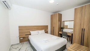 Une chambre d’hôtel avec un lit, un bureau, une chaise et une armoire.