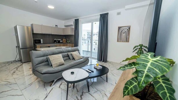 Un salon moderne avec un canapé gris, une petite table basse et une grande plante.