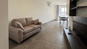 Ein modernes Wohnzimmer mit Sofa, Esstisch und Küchenzeile.