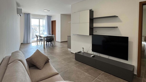 Ein modernes Wohnzimmer mit einer Couch, Fernseher und integrierten Regalen.