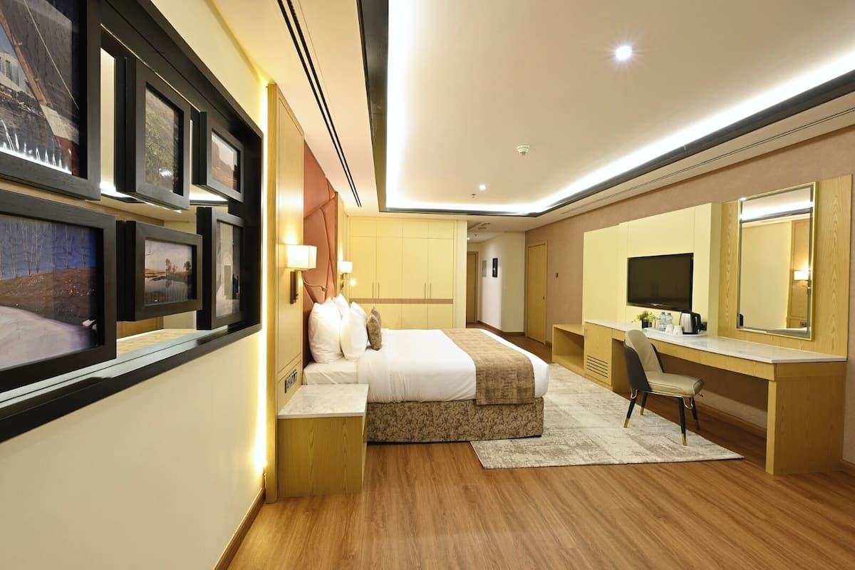 A modern hotel room with a bed, desk, and large mirror.