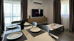 Un comedor moderno con una mesa larga, sillas y un televisor de pantalla plana que muestra 'NETFLIX'.