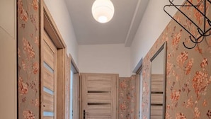 A hallway with a wooden door, a mirror, a sink, and a patterned carpet.