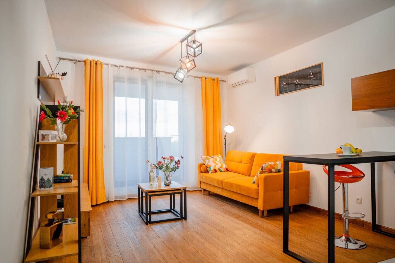 Ein modernes Wohnzimmer mit Holzboden, einer Couch, einem Couchtisch und einem Bücherregal.