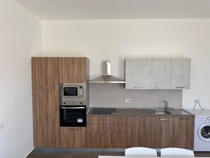 Una cocina compacta con horno integrado, microondas y lavadora.