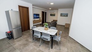 Un espace de vie compact comprenant un coin repas, une kitchenette et un téléviseur.