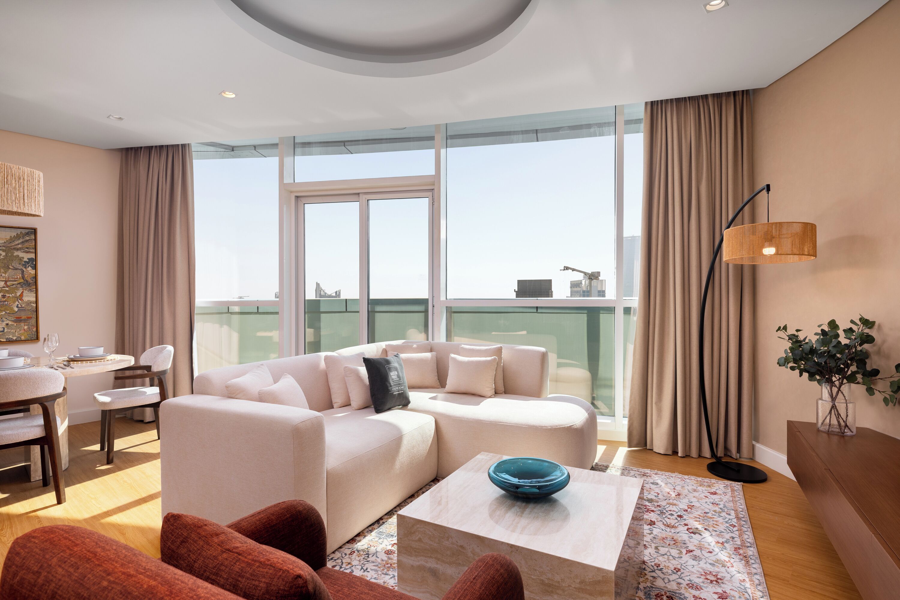 A modern living room with a sofa, coffee table, and a view of the city through large windows.