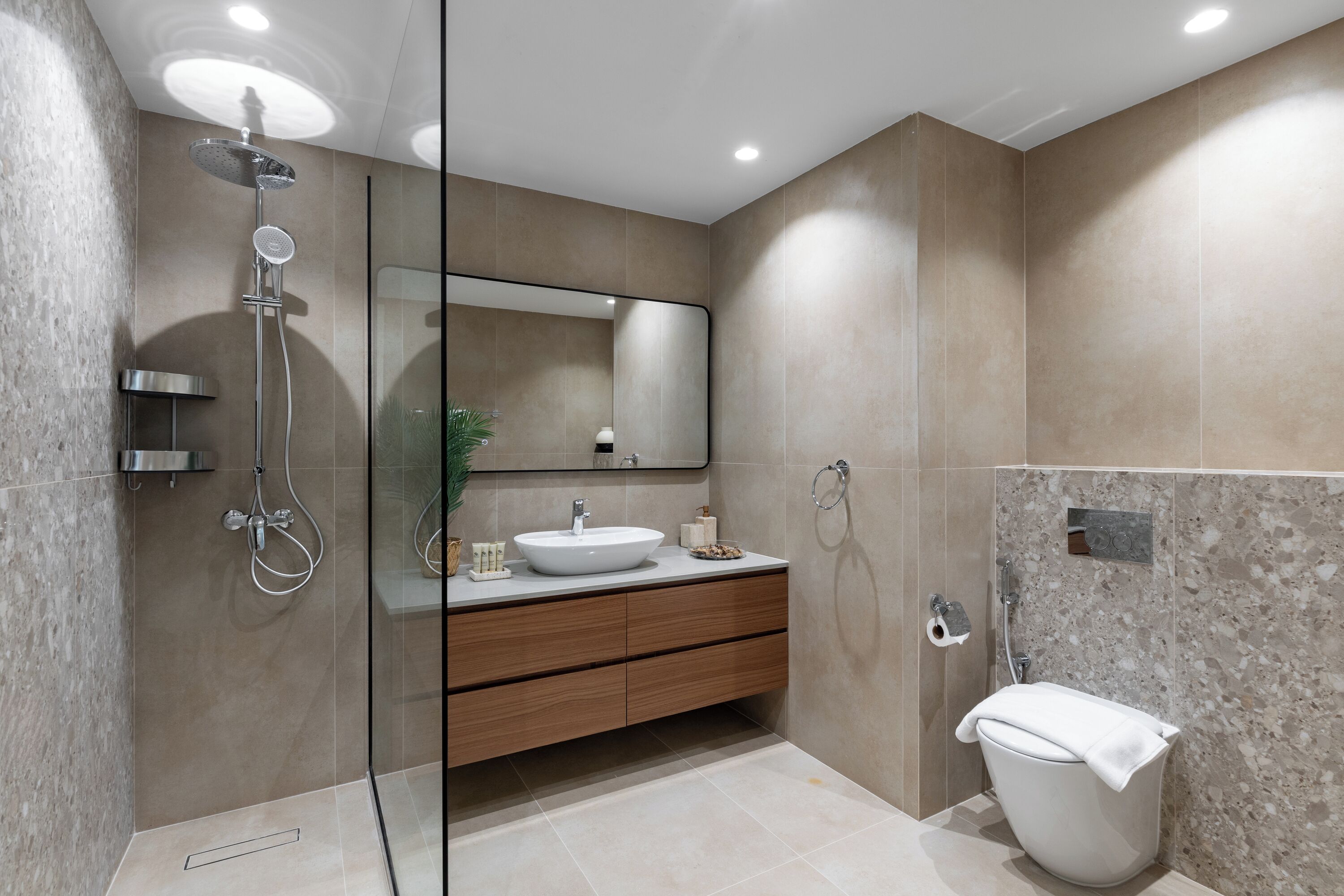 Een moderne badkamer met een douchecabine van glas, een witte wastafel en een toilet.