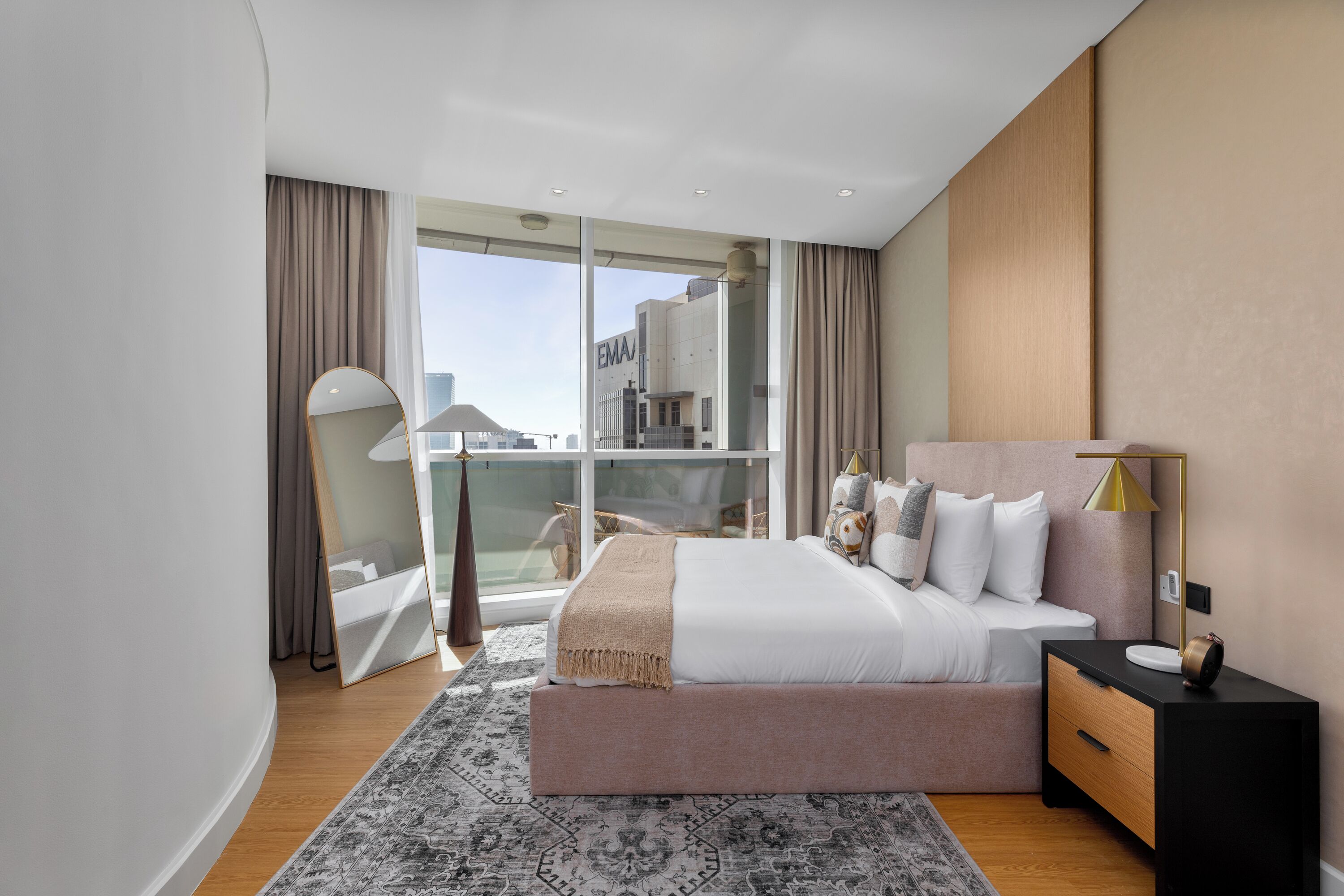 Une chambre d’hôtel moderne avec un grand lit, une table de chevet, un miroir et une vue sur la ville.