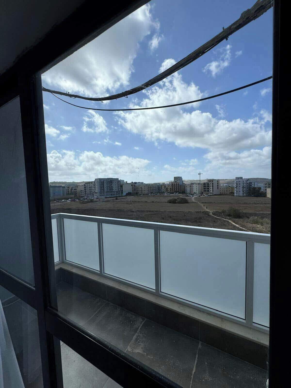 A balcony with a view of a cityscape, including buildings and a clear sky.