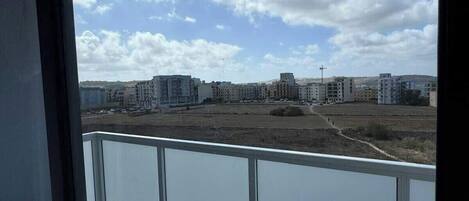 A balcony with a view of a cityscape, including buildings and a clear sky.