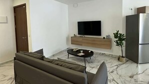 Un salon moderne comprenant un canapé, un téléviseur, une table basse et un réfrigérateur.