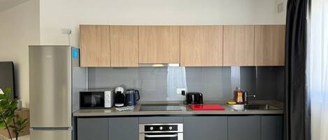 Una cocina moderna con horno empotrado, microondas y cafetera.