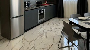 Une cuisine moderne équipée d’un four encastré, d’un réfrigérateur et d’un coin repas avec une table et des chaises.