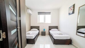 Un dormitorio moderno con dos camas, una ventana, una mesita de noche y un espejo.