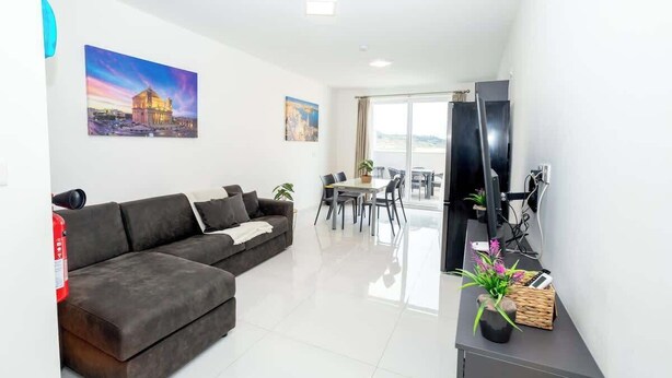 Una sala moderna con un sofá, una mesa de comedor y un televisor.