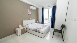 Un dormitorio moderno con cama, mesitas de noche, una silla y vistas al exterior a través de una ventana.