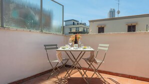 A small outdoor balcony with a table set for two, featuring a bottle and glasses. - Molo Angioino Suites (Naples)