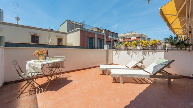 A rooftop terrace with a table and chairs, a lounge area with sun loungers, and a view of neighboring buildings. - Molo Angioino Suites (Naples)