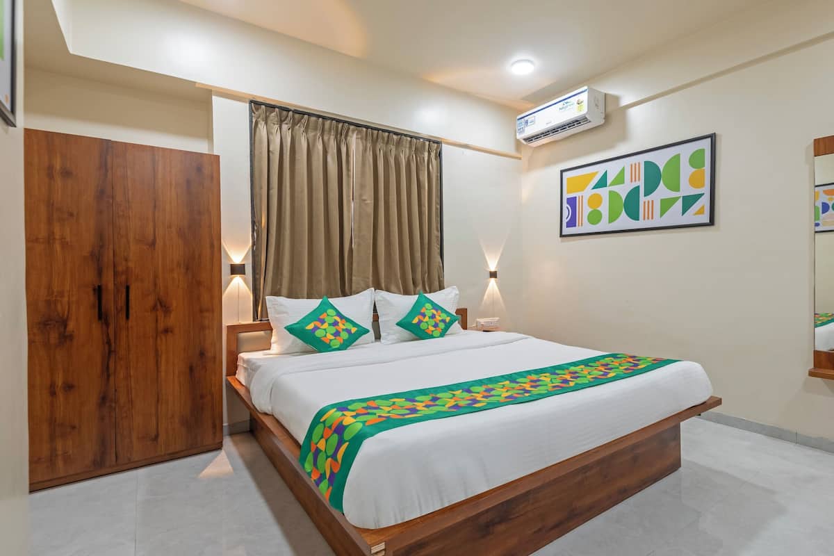 A hotel room with a wooden bed, beige curtains, a wall-mounted air conditioner, and a framed abstract painting.