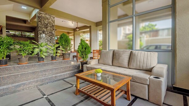 A modern lobby with a sofa, coffee table, and potted plants. - Treebo Sunrise Apartments (Pune)